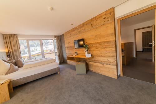 a bedroom with a wooden wall with a bed and a desk at Aparthotel Hochland GmbH in Nauders
