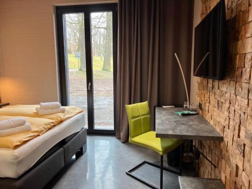 a bedroom with a bed and a desk and a window at Zweirad Hotel Lenne in Schwerin