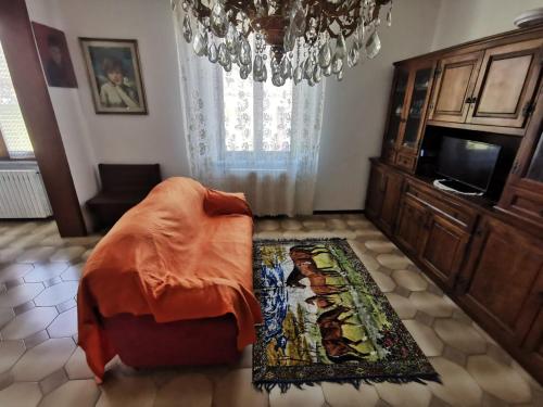 1 dormitorio con 1 cama, TV y lámpara de araña en Appartamento Lucia, en Filattiera