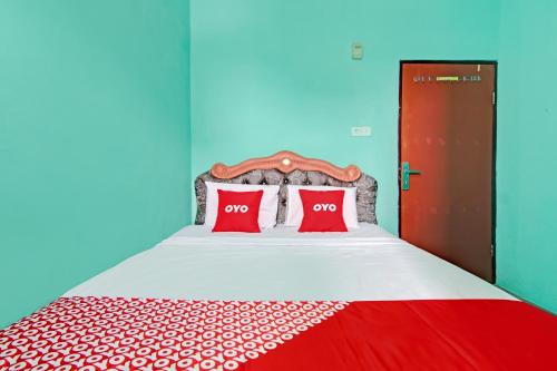 um quarto com uma cama com duas almofadas vermelhas em OYO 3063 Homestay 22 Syariah em Dumai