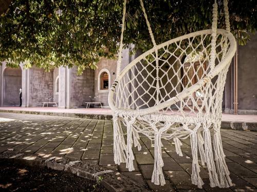 a white swing hanging from a tree in a courtyard at Santoro Country House in Castiglione di Sicilia