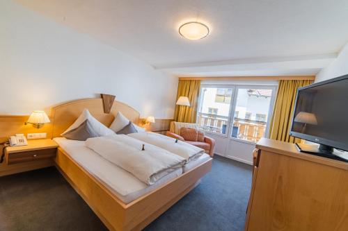 a hotel room with a bed and a flat screen tv at Aparthotel Hochland GmbH in Nauders