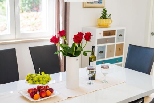 a table with a vase of roses and a bottle of wine at Villa Rubea in Cavtat