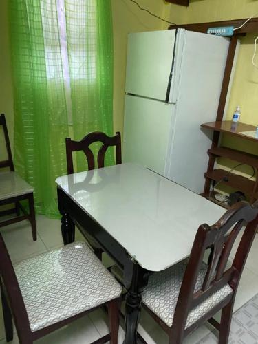 a table and chairs in a kitchen with a refrigerator at Anne's Homestay in Banse