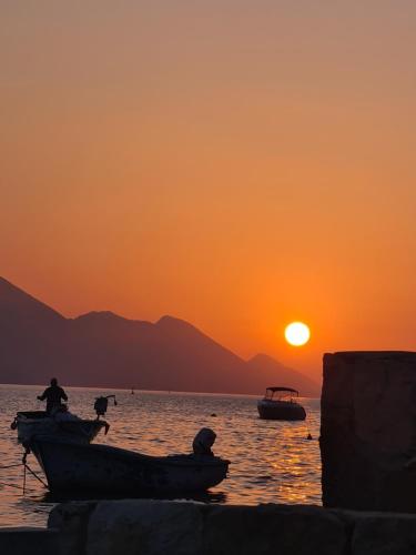 dos barcos en el agua con una puesta de sol en el fondo en Apartments Mediteraneo, en Klek