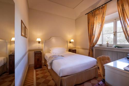 a bedroom with a bed and a desk and a window at QC Grand Hotel Roma in Fiumicino