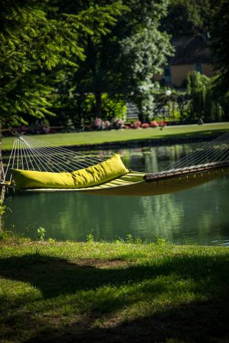 a hammock in a park next to a body of water at Abbaye de la Bussière in La Bussière-sur-Ouche