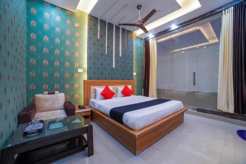 a bedroom with a bed and a chair and a table at Hotel Anand International in New Delhi