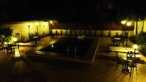 a swimming pool in a courtyard at night at Hotel Bakos in Loutraki
