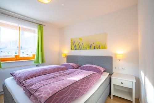 a bedroom with a bed with purple comforter and a window at Alpenliebe Ferienwohnung in Ofterschwang