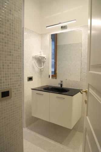 ein weißes Badezimmer mit einem Waschbecken und einem Spiegel in der Unterkunft Gemelli Hotel in Rom
