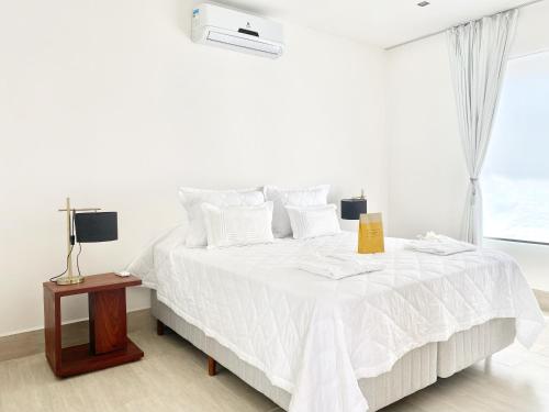 a bedroom with a white bed and a window at Blanc Residence in Pipa
