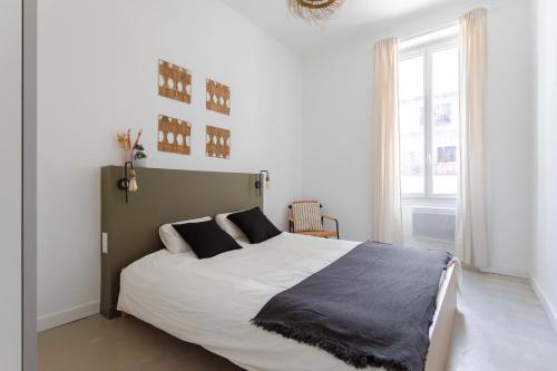 a white bedroom with a large bed with black pillows at Charmant T3 à proximité du Vieux-Port in Marseille