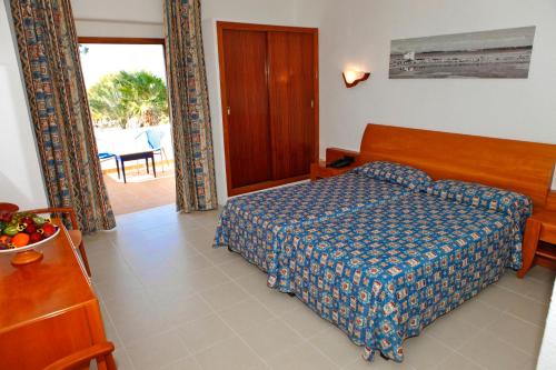 a bedroom with a bed with a blue comforter at Hotel Ca Marí in Playa Migjorn
