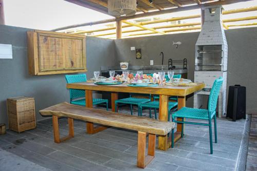 einen Esstisch mit Stühlen, einem Tisch und einer Bank in der Unterkunft Casa Riacho in São Miguel dos Milagres