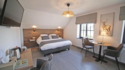 a hotel room with a bed and a table and chairs at Auberge la Hutte Lurette in Paliseul