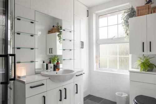 a white bathroom with a sink and a window at St Owen's Terrace by RentMyHouse in Hereford