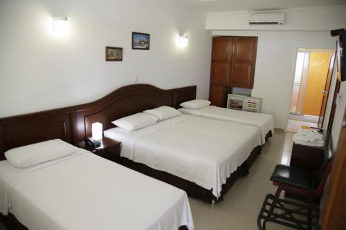 a hotel room with two beds and a chair at Hotel Los Puentes Comfacundi in Girardot