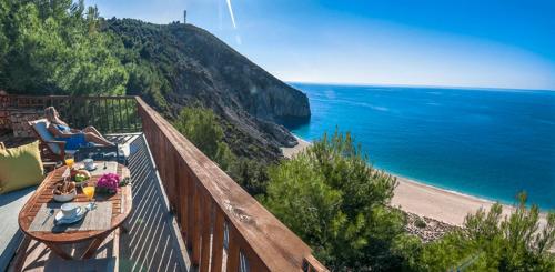 a woman sitting on a balcony looking at the ocean at Beyond Villas in Agios Nikitas