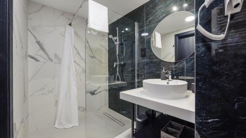 Baño en blanco y negro con lavabo y espejo en Apartamenty Sun & Snow Solny Resort en Kołobrzeg