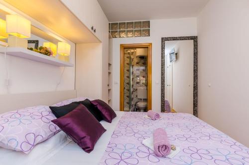 a bedroom with a large bed with purple pillows at Apartments & Room Frane in Dubrovnik