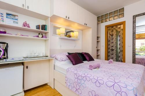 um pequeno quarto com uma cama com almofadas roxas em Apartments & Room Frane em Dubrovnik