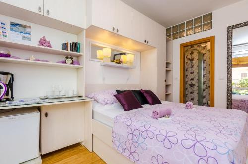 a small bedroom with a bed with purple pillows at Apartments & Room Frane in Dubrovnik