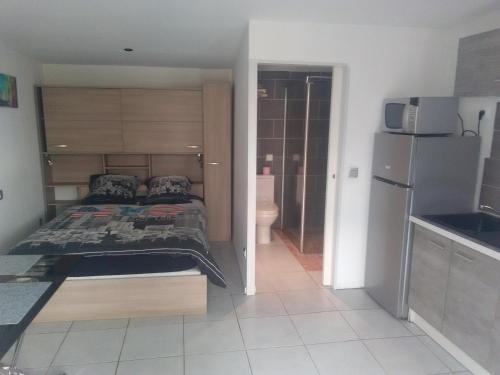 a small bedroom with a bed and a refrigerator at Studios - Bord de Plage in Vias