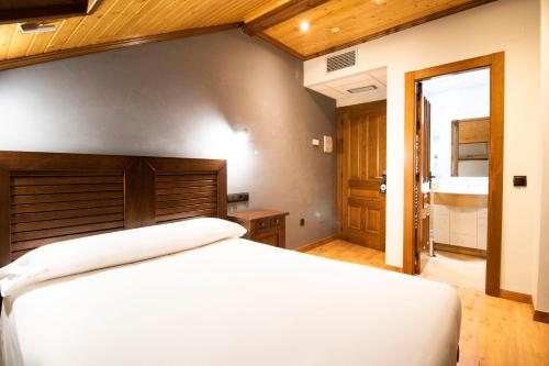 a bedroom with a large white bed and a bathroom at Alda Casco Antiguo in León