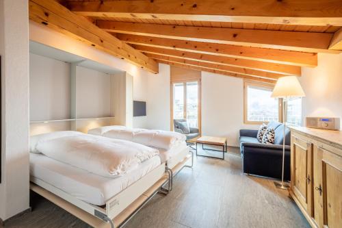 a bedroom with two beds and a couch at Casa Darschalè 11 in Laax