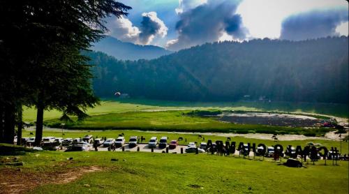 a group of people standing in a field near a lake at Edenroc.khajjiar in Khajjiar 