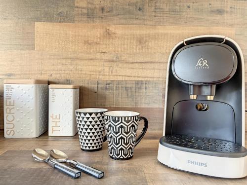 une cafetière à côté de deux tasses et cuillères dans l'établissement Appart XL 