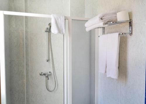 y baño con ducha y toallas blancas. en Alda Vía de la Plata Rooms, en La Bañeza