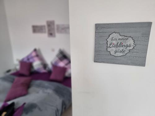 a bedroom with a bed with purple pillows and a sign at Pension Heuhexe in Fladungen