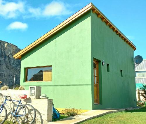 une maison verte avec un vélo garé devant elle dans l'établissement La Ribera - Saint Exupéry 90, à El Chalten