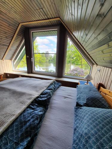 a large bed in a room with two windows at Ferienhaus blauer See mit optionalem Hot-Tub in Bockhorn