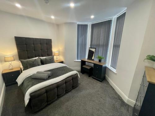 a bedroom with a large bed and two windows at Osborne luxury hot tub and jacuzzi suites in Blackpool