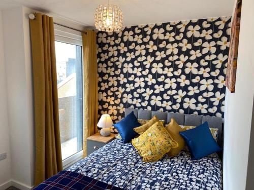 a bedroom with a bed with blue and yellow pillows at Central 2 bed Newly built DUPLEX Penthouse with FREE Gated, On-site Parking, Lift access, Self Check-in, SUPER Fast WIFI, TWO Cathedral view Terraces & Sleeps 6 in Peterborough