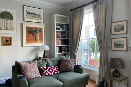a living room with a green couch and a window at Comfortable 2 Bedroom Apartment in Lavish Holland Park with Balcony in London