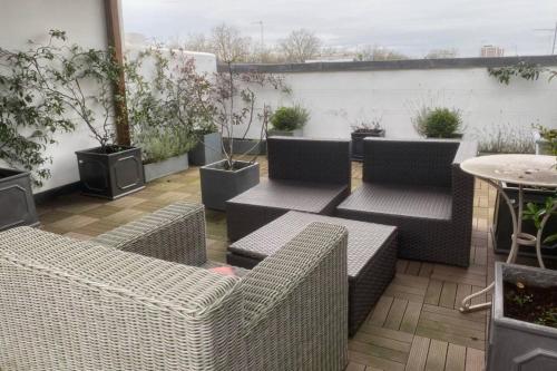 a patio with wicker chairs and tables and potted plants at Comfortable 2 Bedroom Apartment in Lavish Holland Park with Balcony in London