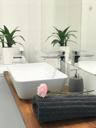 a bathroom with a sink and a flower on a counter at Apartament Czechowska Luxury in Lublin