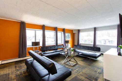 a living room with black leather furniture and orange walls at Hotel Royal Oak in Royal Oak