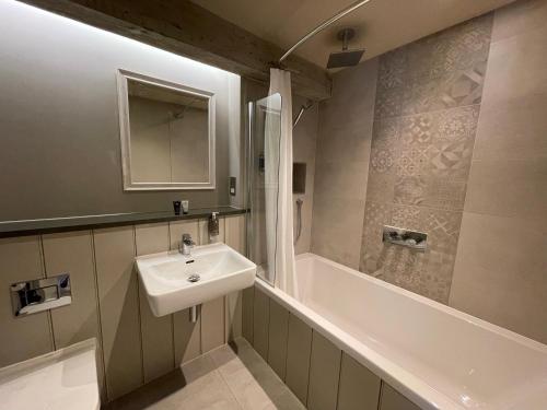 a bathroom with a sink and a shower and a tub at Park Farm Hotel in Norwich