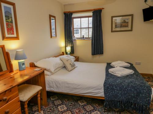 1 dormitorio con cama, escritorio y ventana en Wheelhouse Cottage, en Whitby