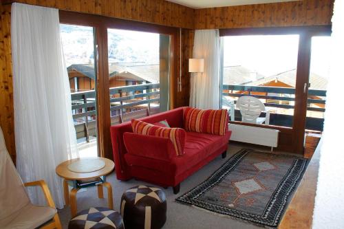 ein Wohnzimmer mit einem roten Sofa und einem großen Fenster in der Unterkunft Combyre COMFORTABLE & CENTER apartements in Veysonnaz