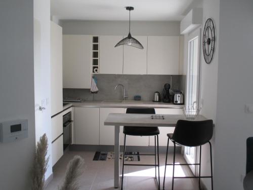 une cuisine avec des placards blancs, une table et des tabourets dans l'établissement Sanary Paradise, à Sanary-sur-Mer