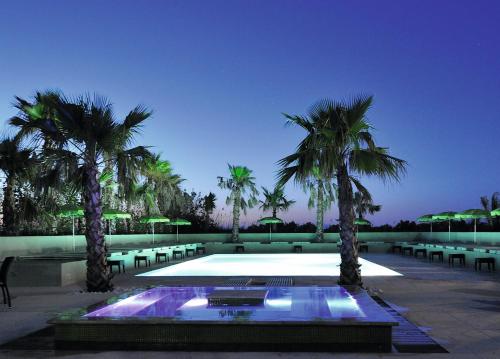 a swimming pool with palm trees in a resort at Le Jardin de Babylone "r&eacute;serv&eacute; aux couples uniquement" in Cap d'Agde