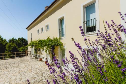 a white house with purple flowers in front of it at Retiro do Bosque Country House in Minde