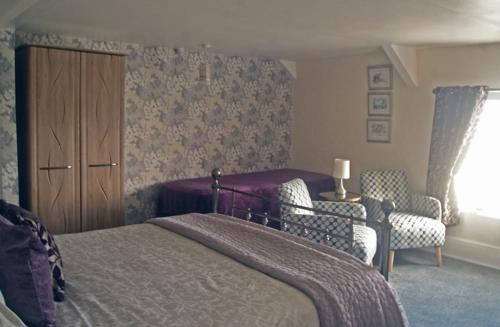 クロベリーにあるThe Old Smithy Bed & Breakfastのベッドルーム1室(ベッド1台、椅子2脚、キャビネット付)