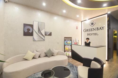 a lobby with a white couch and a woman behind a counter at Green bay hotel Ha Long in Ha Long